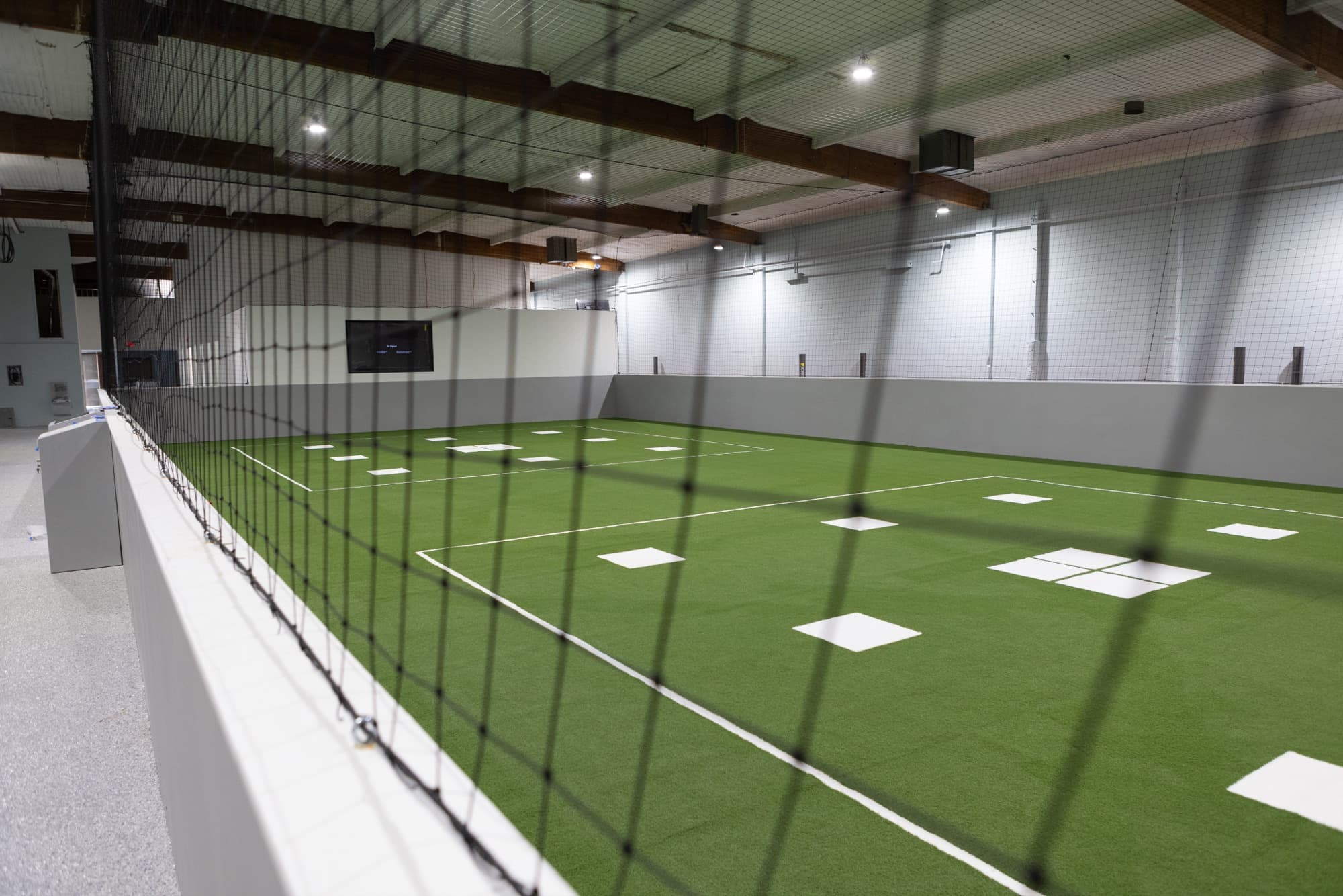 Match-grade indoor turf training lanes with perimeter netting at Formula Soccer Center.